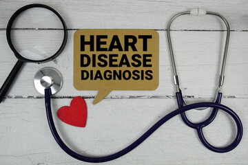 Heart Disease Diagnosis text with Red heart, Magnifying glass and Medical Stethoscope on wooden background