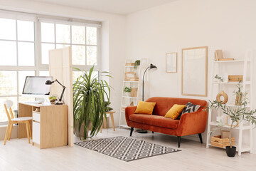 Interior of stylish living room with brown sofa, folding screen and comfortable workplace