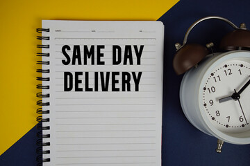 Same Day Delivery text written on notepad with alarm clock on yellow background