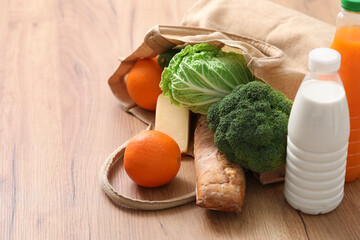 Shopping bag with different fresh products on wooden background