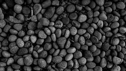 a collection of small, rounded, and smooth pebbles in black and white background