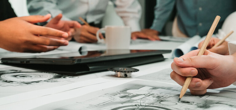 A dynamic brainstorming session featuring hands engaged in sketching and discussing designs with digital tools in a modern office setup, showcasing teamwork and creativity. SACTR