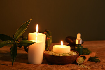Spa composition with burning candles and bamboo stem on dark wooden table