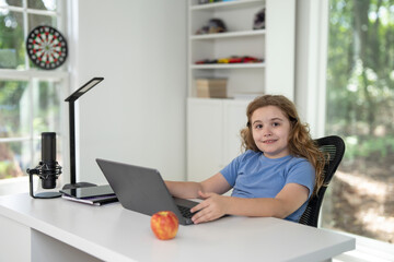 Kid learning at home with laptop and books. Child learn online using laptop at desk. Learning with homework in child room. E-learning on laptop. Kid learning at home. Interior with kid and laptop.