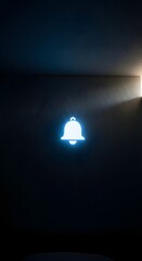 A glowing notification bell icon illuminated against a dark wall, symbolizing alerts or notifications in a digital environment
