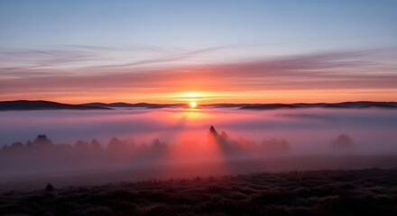 A breathtaking sunrise over a foggy landscape with vibrant colors illuminating the sky and creating a serene atmosphere at dawn