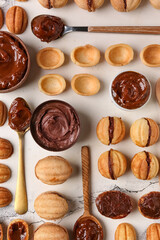 Sweet walnut shaped cookies with boiled condensed milk and bowls of sauce on white background