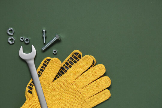 Tap bolts, gloves and wrench on green background