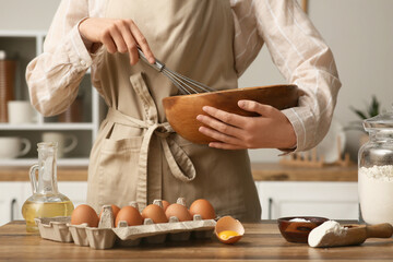 Woman mixing ingredients in bowl for preparing dough on kitchen counter