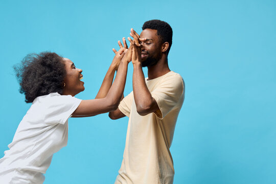 Happy couple playfully interacting against a vibrant blue background, showcasing joy and connection in casual attire, perfect for social media and lifestyle themes - Powered by Adobe