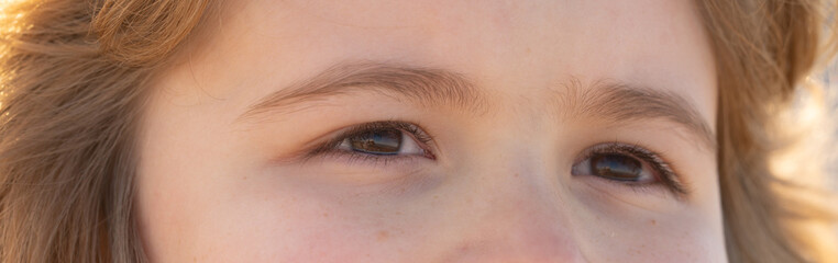 Obraz premium Child eyes in sunlight close-up. Kid eyes macro. Warm light on child face. Soft focus portrait of kid. Kid looking away. Daydreaming kids eyes. Close-up eyes of blond Boy.