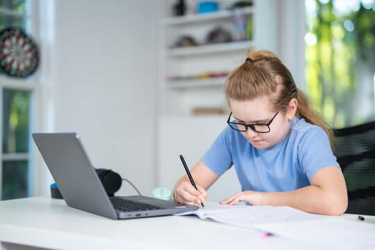 Kid studying mathematics on laptop during e-learning session. Student streaming online lesson. Child doing schoolwork in home classroom interior. Online education and digital study.