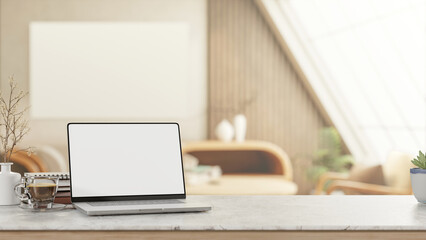 White screen laptop with coffee and book on marble counter table in attic living room with sunlight.