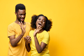 Happy young African couple in matching yellow outfits, smiling and enjoying a joyful moment against a vibrant yellow background Emotional and playful expression