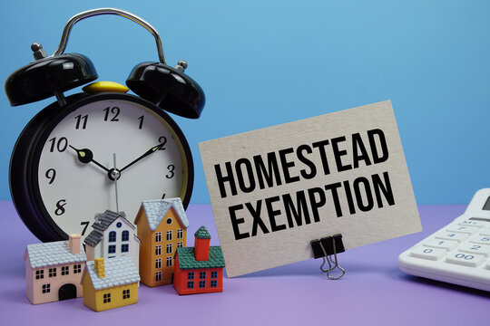 Homestead Exemption phrase with Calculator, alarm clock, Model Houses Real Estate Financial Concept