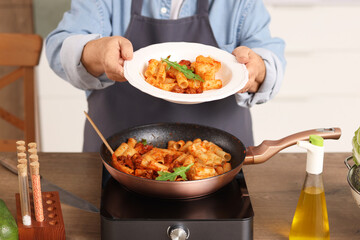 Senior woman with fried pasta in kitchen, closeup
