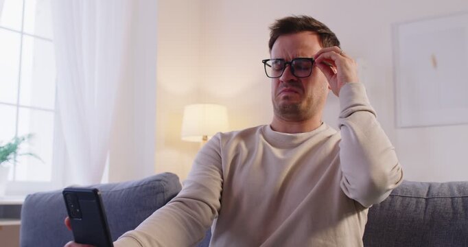 Eyewear problem, man watching phone screen, wrong glasses, feels unwell having dizziness or blurry vision, reading serious important message on phone screen, unexpected news, fixing problem solution 