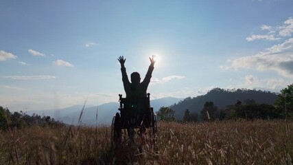 Silhouette Woman sitting on a wheelchair enjoying with raised hands on the mountain sunset time. - Powered by Adobe
