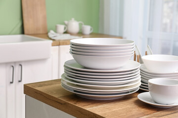 Clean white dishes on wooden table in kitchen