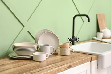 Holder with clean plates and cups near sink on counter in kitchen