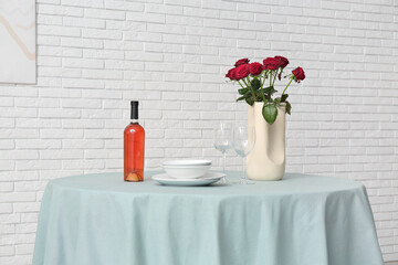 Vase with roses and dishes on mint tablecloth in dining room