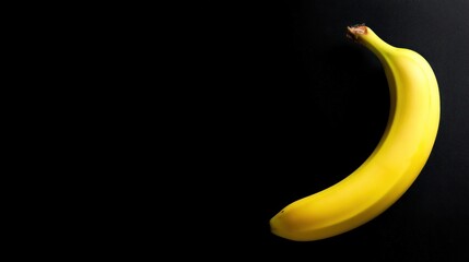 Curved banana is isolated on a sleek black background in a studio shot
