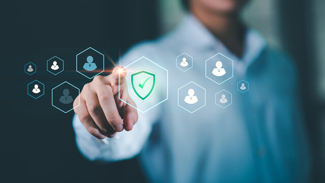 Businessman interacting with a digital interface showing user icons and a security shield, representing workplace safety, employee data protection, secure management systems in modern organizations.