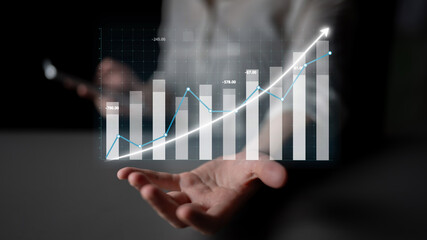 A businessman holds a smartphone while displaying a digital growth chart overlay, illustrating financial success and market analysis in modern business settings. Impute