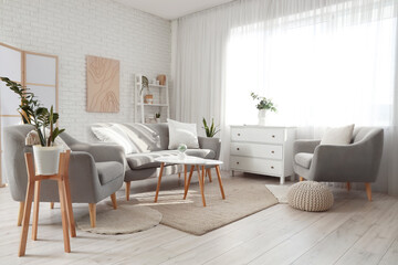 Interior of light living room with curtain, sofa and armchairs