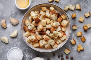 Bowl with crunchy croutons and different spices on grey background