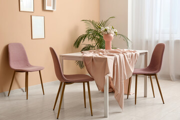Table and chairs near beige wall in interior of dining room