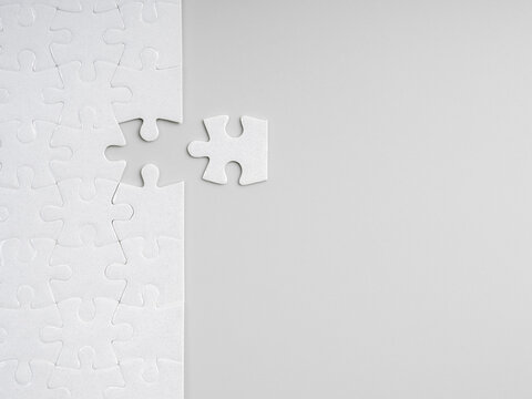 Minimal white puzzle with missing piece on grey background with copy space. Concept of solution, strategy, problem solving, business planning, completion, finding the right fit, and filling the gap.