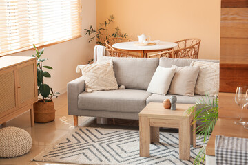 Interior of stylish living room with comfortable beige sofa and tables near beige wall, closeup