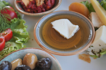 Delicious spread featuring olives, feta cheese, herbs and honey on a plate.