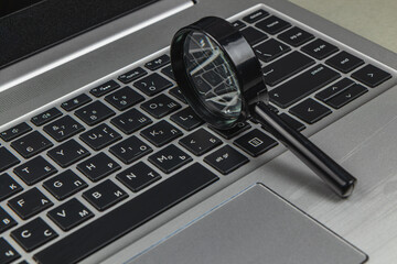Magnifying glass placed on a laptop keyboard in an office setting