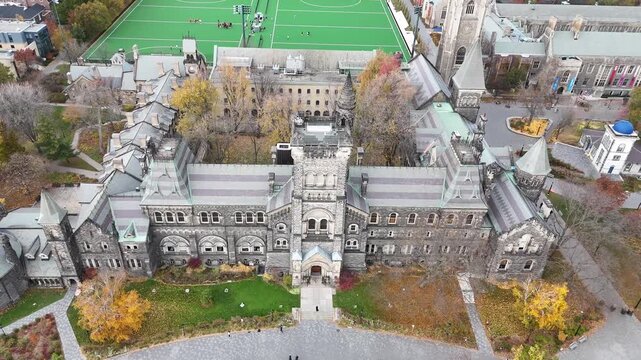 Cinematic shot pulls out from the top of the University College building at the University of Toronto, tilting the camera upward to reveal the full historic Romanesque facade and main entrance