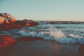 Coastal Sunset Scene Waves Crashing Against Rocks with Teal Water and Golden Hour Lighting