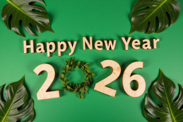 Happy new year 2026. Wooden cube with the number 2026 with tropical leaves monstera on green background. Top view. Start concept. 3d rendering.