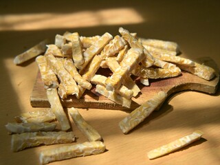 Raw tempeh slices in stick form on a wooden cutting board. Preparing to cook tempeh. Preparing to eat tempeh.