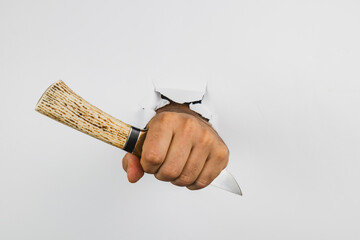 Hand with knife breaking through white wall creates striking visual impact