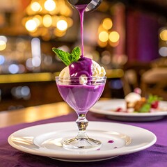 A scoop of white ice cream topped with a vibrant purple sauce and a mint leaf, in a clear glass on a white plate