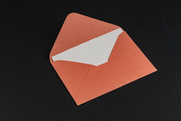 Orange envelope with a white insert lying on a black background
