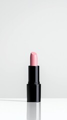 A close-up shot of a pink lipstick in a black tube, presented vertically against a clean, bright white backdrop with its reflection visible below.