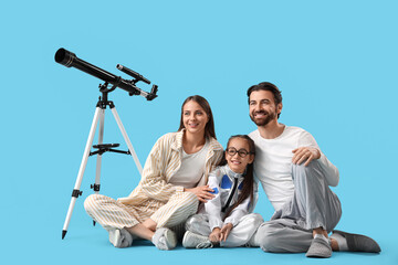 Little girl in astronaut costume with her parents and telescope sitting on blue background