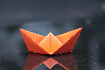 Origami boat floating on shallow water puddle outdoors, closeup