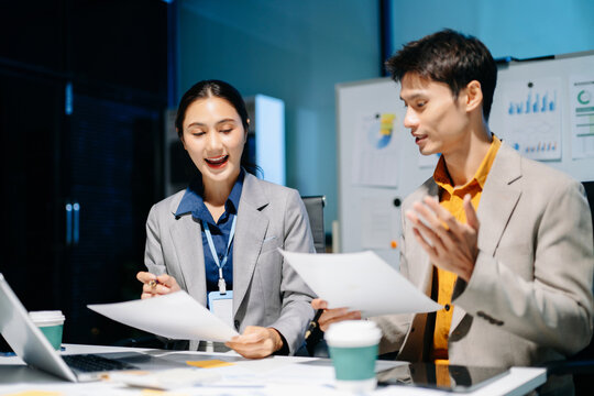 business team working late at night, reviewing documents and discussing project details with a laptop and calculator. Ideal for concepts of teamwork
