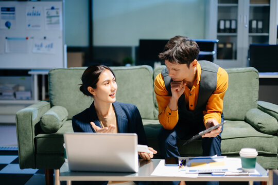 business team working late at night, reviewing documents and discussing project details with a laptop and calculator. Ideal for concepts of teamwork