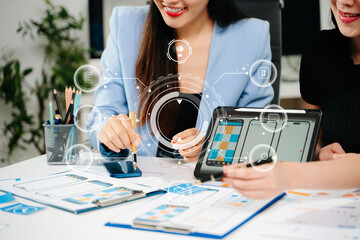 UX UI designers reviewing mobile app interface elements on a digital tablet, showcasing teamwork,...