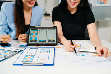 UX UI designers reviewing mobile app interface elements on a digital tablet, showcasing teamwork, creative planning, and modern app design