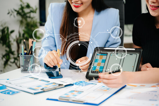 UX UI designers reviewing mobile app interface elements on a digital tablet, showcasing teamwork, creative planning, and modern app design